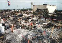 A government photo of U.S., Texas, and AFT flags which law enforcement raised over the charred rubble of the Branch Davidian compound after the standoff and siege resulted in the fire that killed more than 70 people.